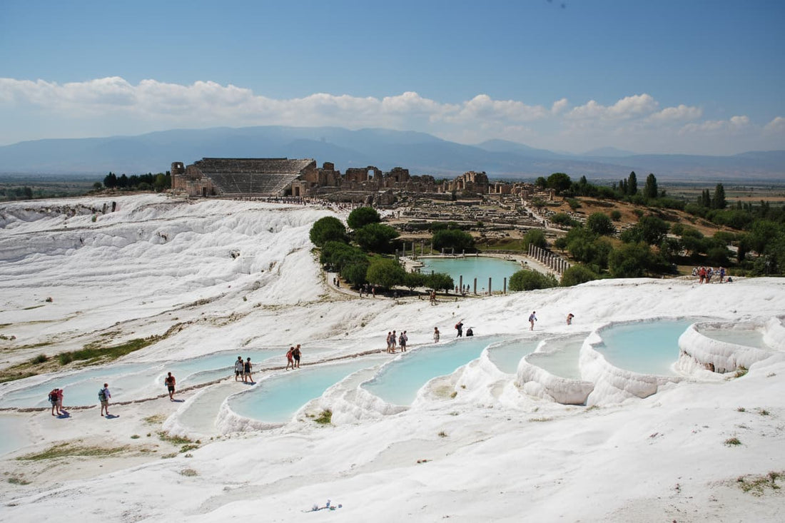 Pamukkale Turkey – stunning white calcium carbonate travertine terraces with warm turquoise mineral pools cascading down hillside, ancient Hierapolis ruins above, UNESCO World Heritage Site Cotton Castle