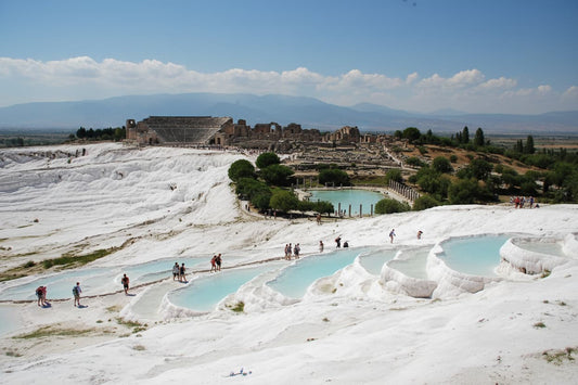Pamukkale Turkey – stunning white calcium carbonate travertine terraces with warm turquoise mineral pools cascading down hillside, ancient Hierapolis ruins above, UNESCO World Heritage Site Cotton Castle